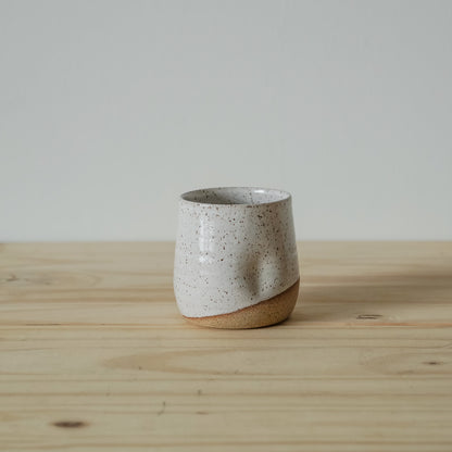 Handmade speckled white ceramic tumbler with exposed clay base and softly faceted form by Good Wheel Ceramics.