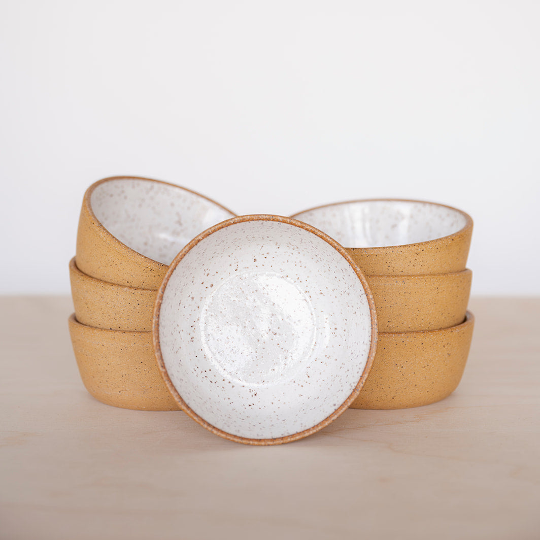 Set of Good Wheel Ceramics Snack bowls with textured rim and outside and glossy white glaze on the inside on a neutral background. Shows the size and roundness of these bowls. 