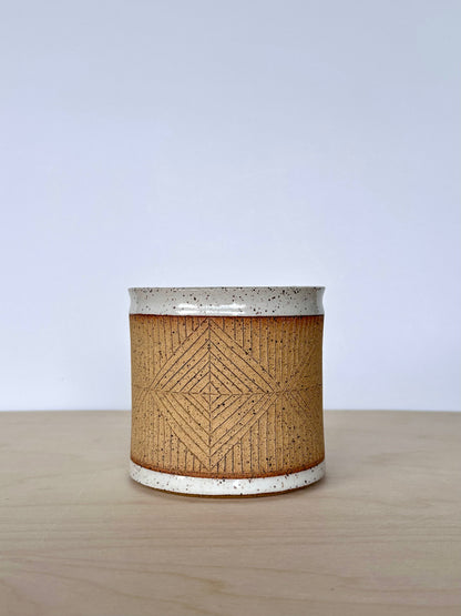 Close up of handmade wheel-thrown ceramic mug with hand-carved diamond pattern. 