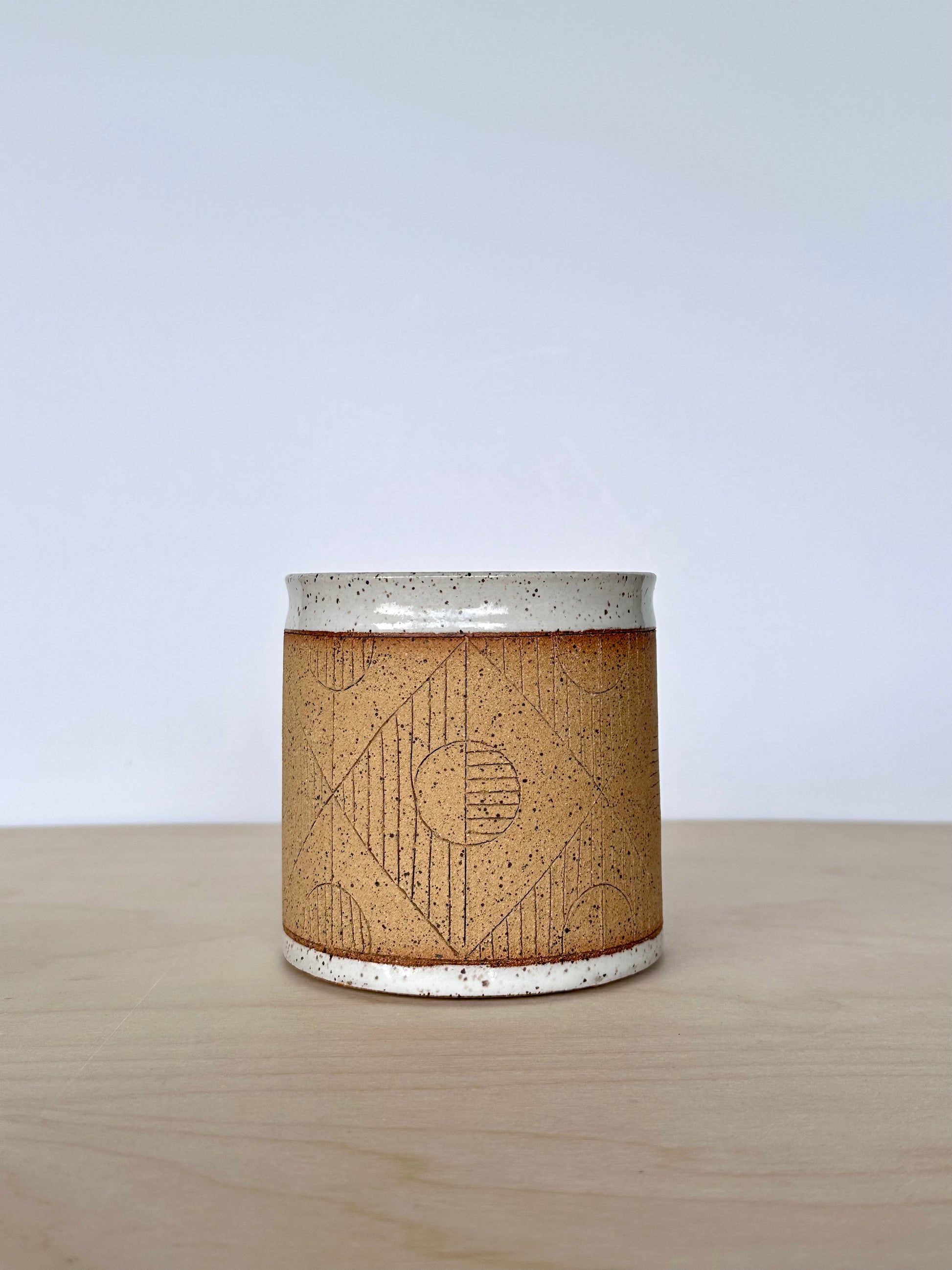 Close up of handmade wheel-thrown ceramic mug with hand-carved circle pattern. 