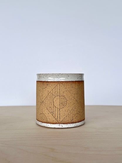 Close up of handmade wheel-thrown ceramic mug with hand-carved circle pattern. 